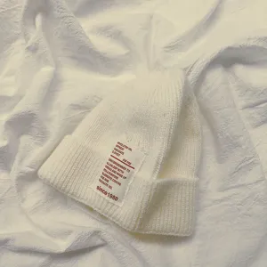 Vista dettagliata berretto maglia bianca, caldo cappello di lana inverno con etichetta testo.