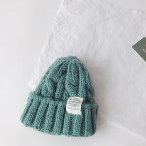 Kids cable knit beanie hat detail view, soft warm winter pullover cap with fabric label.