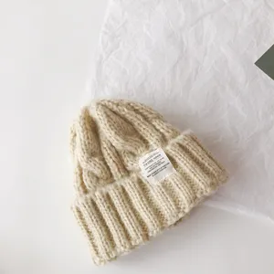 Details of the children cable knit beanie in beige with stylish cloth label for winter warm wear.