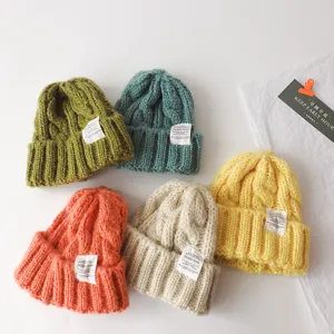 Kids cable knit beanie detail shot, featuring cozy woolen texture and cute cloth label.