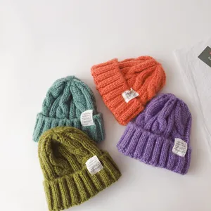 Close-up detail view of colorful cable knit children beanies in soft winter wool material.