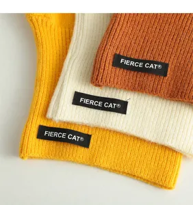 Detailed view of kids knitted winter warm hat in yellow, beige and caramel, soft texture.