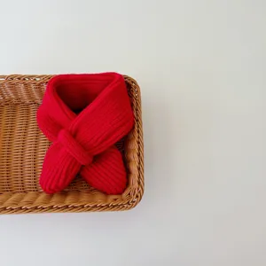 Red knitted baby scarf detail view, minimalist cross design, warm wool neck warmer kids.
