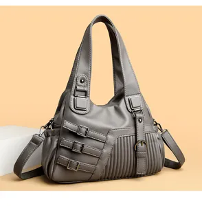 Detailaufnahme der grauen weichen Ledertasche mit dekorativen Metall Schnallen und Falten.