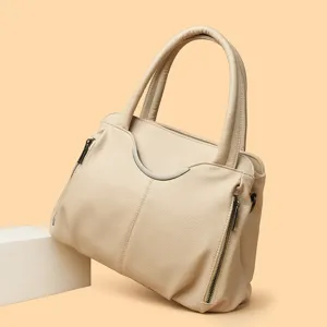 Beige lederen handtas voor dames, elegante handtas met handvat en metalen accentdetail.
