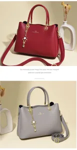 Detailansicht der eleganten Handtasche aus Leder mit Blumenanhänger und goldener Hardware.