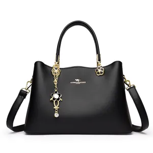 Elegante schwarze Handtasche aus Leder für Damen mit goldenen Beschlägen und Anhänger.