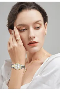 Detail shot of a women's silver and gold stainless steel quartz watch worn on the wrist with elegant jewelry.
