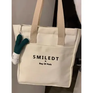 Casual canvas tote bag for women, large capacity shoulder commuting bag with cute plush pendant.