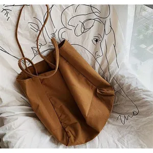 Detailed shot of a minimalist brown canvas tote bag with slim straps on artistic fabric.