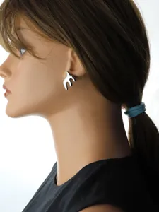 Detailed view of silver abstract swallow ear studs worn on a mannequin, minimalist style.