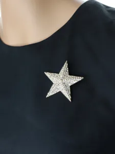 Close-up of a sparkling rhinestone star brooch on black fabric, elegant jewelry accessory.