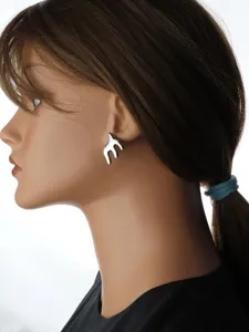 Detailed side view of shiny silver abstract swallow stud earrings worn by mannequin