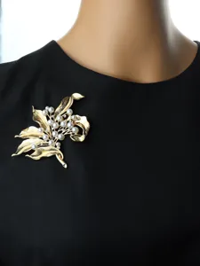 Vintage gold-tone floral brooch detail featuring elegant pearl and rhinestone decor.