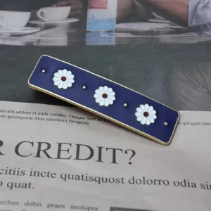 Close-up detail of the retro navy blue enamel daisy hair clip showing delicate floral pattern.