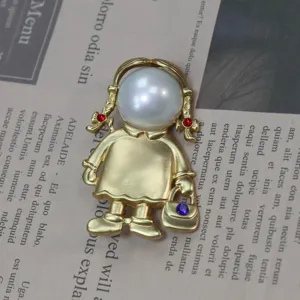 Spilla vintage in oro opaco a forma di bambina con grande perla e brillanti strass.