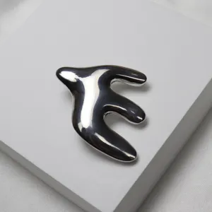 Exquisite abstract swallow brooch detail view, smooth metallic finish, elegant garment accessory.