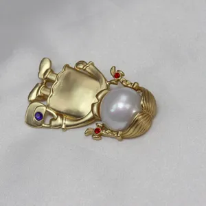 Dettaglio spilla vintage bambina perla oro opaco, accessorio di abbigliamento elegante donna.