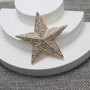 Close-up detail of the elegant gold tone star shaped brooch with sparkling rhinestone.