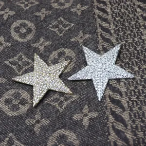 Detail view of sparkling rhinestone star brooches in gold and silver, perfect for apparel decoration.