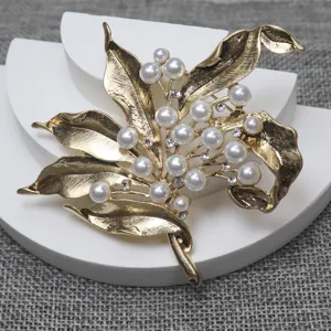 Vintage gold-tone leaf brooch with faux pearls and rhinestones, elegant costume jewelry accessory.