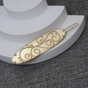 Close-up detail of the vintage gold hairpin, highlighting its embossed scroll texture.