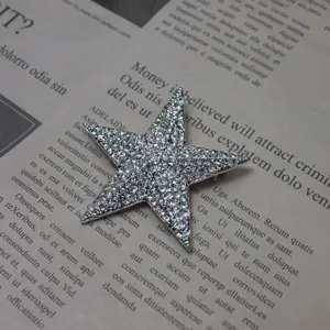Close-up view of a sparkly rhinestone five-pointed star brooch on vintage newspaper.