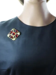 Vue détail de broche vintage dorée avec verre rouge, accessoire de bijouterie élégant.