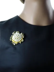 Détail de broche fleur dorée avec perles, accessoire élégant pour décorer vos vêtements.