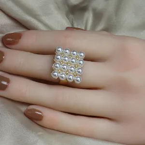 Bague statement réglable de couleur dorée avec une matrice carrée de perles blanches.