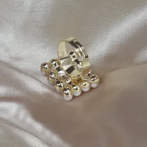Vue détaillée d'un élégant anneau doré réglable décoré de perles blanches sur satin.