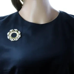 Antike goldfarbene Perlenkranz Brosche elegant präsentiert auf einem schwarzen Kleid.