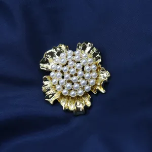 Gros plan détaillé de la broche fleur vintage avec perles délicates et pétales dorés texturés.