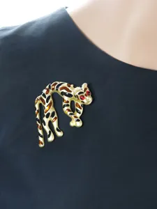 Spilla vintage a forma di leopardo in smalto dorato con occhi di pietra rossa, elegante.