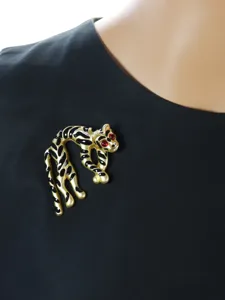 Spilla vintage a forma di leopardo in smalto, metallo dorato con macchie nere e occhi rossi.