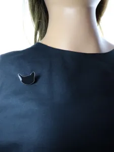 Vue détaillée d'une élégante broche chat en émail noir, accessoire de mode minimaliste chic.
