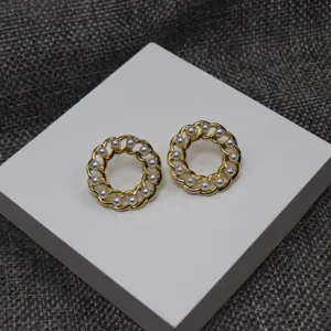 Detail shot of vintage style gold interlocking chain round pearl stud earrings close up view.