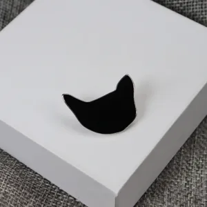 Vue détaillée d'une broche épingle en émail noir chat sur boîte de présentation.