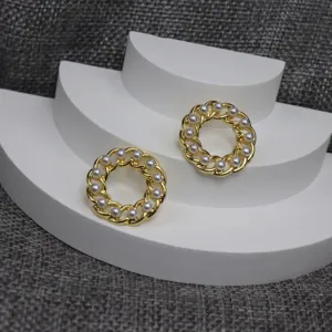 Detail shot of vintage hollow chain round pearl earrings with gold metal and white pearl accents.