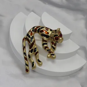 Vista dettagliata della spilla leopardo vintage, metallo dorato con macchie in smalto e occhi rossi.