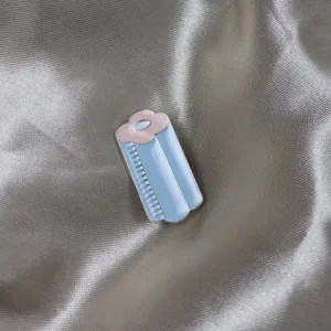 Close-up of creative enamel roll brooch in blue and pink, detailed metal accessory.