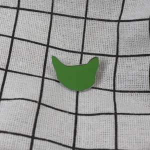 Gros plan sur le détail de la broche chat émaillée verte, design en métal minimaliste.