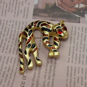 Dettaglio spilla leopardo vintage, metallo dorato con smalto e cristalli rossi luminosi.