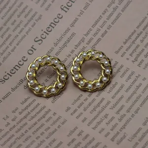 Detailed shot of vintage gold-toned woven chain round pearl earrings on vintage book page.