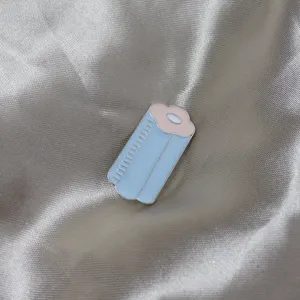Enamel hair curler brooch detail shot, cute blue and pink pin for clothing and bags.