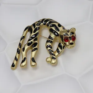 Spilla a forma di leopardo accovacciato color oro con macchie di smalto nero e occhi rossi.