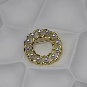 Vintage gold-tone hollow chain round pearl brooch detail shot, elegant jewelry accessory close-up