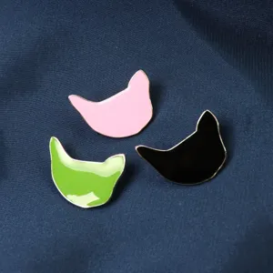 Gros plan de broches chat émaillées minimalistes en rose, vert et noir aux bords métalliques.