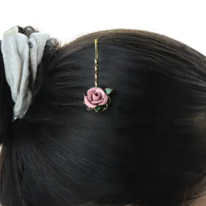 Detailed shot of vintage pink rose hairpin worn in black hair, elegant hair accessory