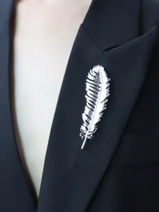Silver feather brooch detail shot, elegant lapel pin accessory for suits and dresses.